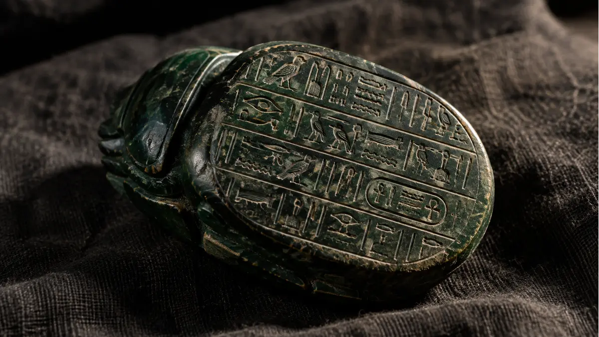Dark green stone heart scarab carved with hieroglyphic text on its underside