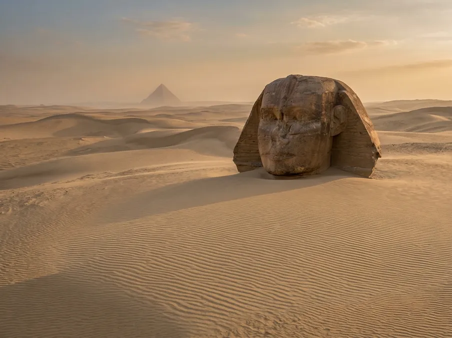 The Great Sphinx buried in sand with only its head visible above the desert